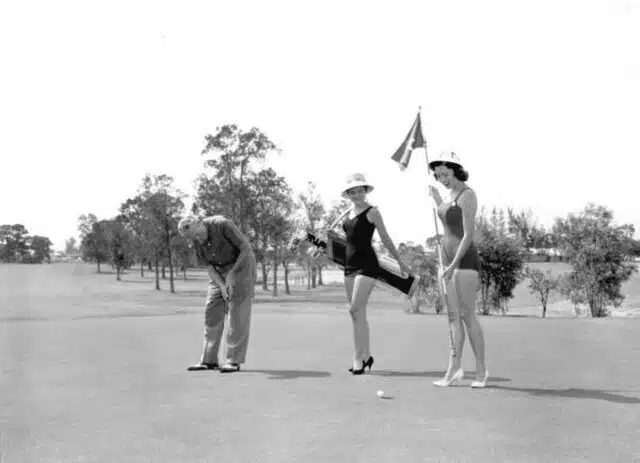 Golfer_with_bathing_beauties_as_caddies_during_the_Tri-County_Suncoast_Festival-_Dunedin,_Florida_(9317334580)