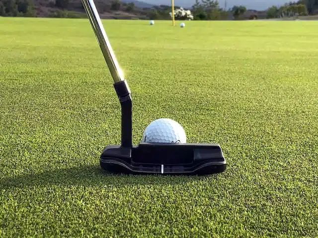 close up of putter about to hit a ball towards the hole